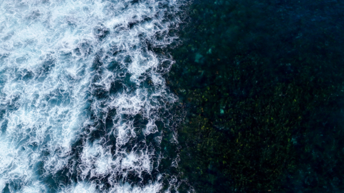 Aerial of white wash meeting the water over shallow reef - Australian Stock Image