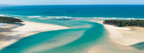 Aerial panorama of a turquoise coastal river flowing out to sea past sand bars and beaches - Australian Stock Image