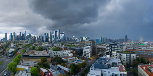 Aerial panorama view of dark storm clouds and rain moving over a distant city skyline - Australian Stock Image