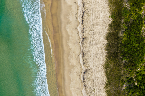 Aerial photo capturing Tuncurry Beach with its golden sand meeting turquoise waters - Australian Stock Image