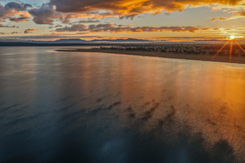 Aerial scene capturing a golden sunrise over Lake Keepit, with morning fog drifting across. - Australian Stock Image