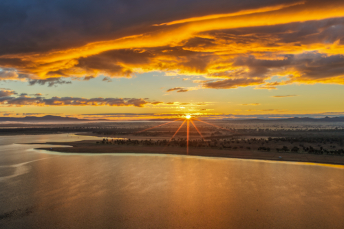 Aerial scene capturing a golden sunrise over Lake Keepit, with morning fog drifting across. - Australian Stock Image