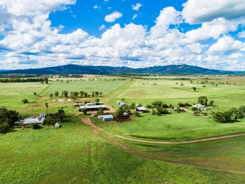 Aerial scene of farm sheds and house among green paddocks - Australian Stock Image