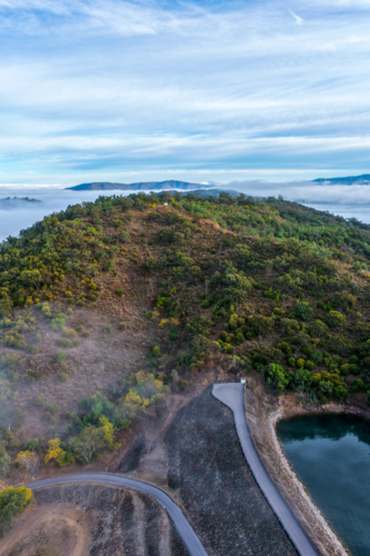 Aerial vertical image of the Glenbawn Dam wall meeting the surrounding mountain landscape - Australian Stock Image