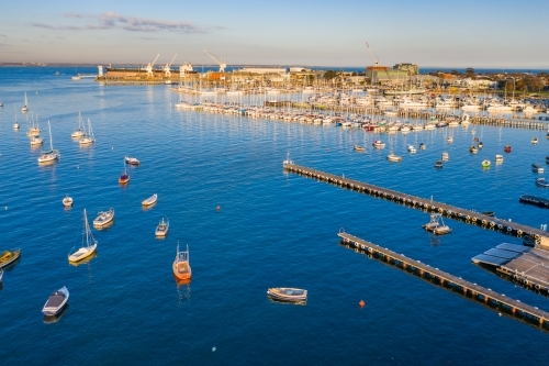 Aerial view a bay side yacht club with long jettys out over the water - Australian Stock Image