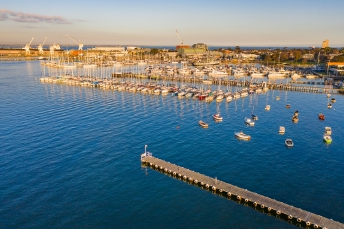 Aerial view a bay side yacht club with long jettys out over the water - Australian Stock Image
