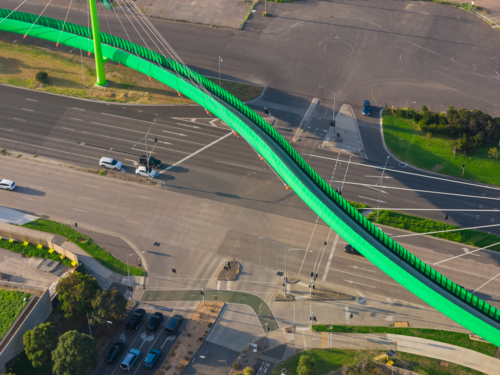 Aerial view of a bright green cycling bridge alongside a highway - Australian Stock Image