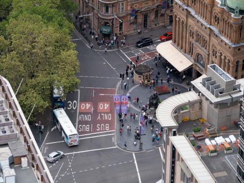Aerial view of a city street intersection with pedestrians and buses