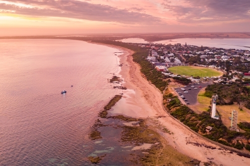 Aerial view of a coastal town and lighthouse at sunset
