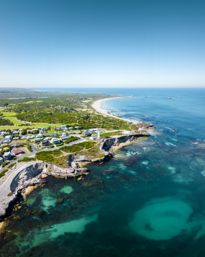 Aerial view of a coastal town atop the rugged limestone cliffs and turquoise shallows - Australian Stock Image