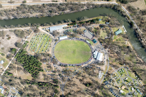Aerial view of a country football ground beside a winding river during a match. - Australian Stock Image