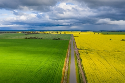 Aerial view of a country road running between rural crops under a dark sky. - Australian Stock Image