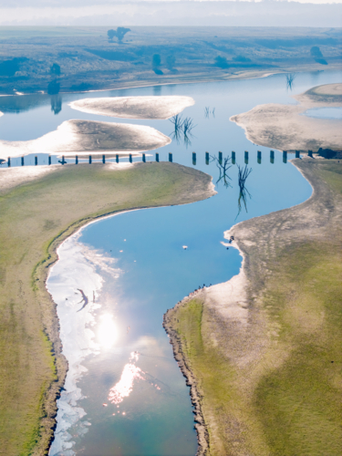 Aerial view of a disused railway bridge through a drying reservoir - Australian Stock Image