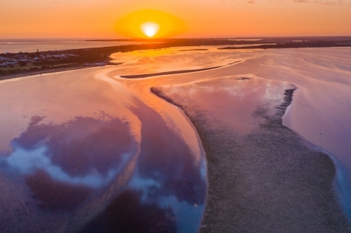Aerial view of a dramatic sunset over islands and reflections in a coastal bay - Australian Stock Image