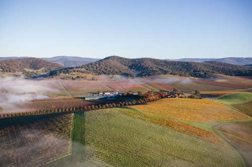 Aerial view of a farmland with farmstead and rolling hills in the background. - Australian Stock Image