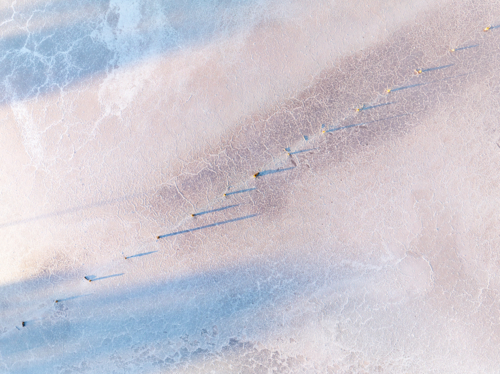 Aerial view of a fence running diagonally through a salt lake - Australian Stock Image