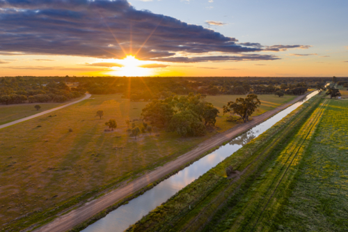 Aerial view of a golden sunset over over an irrigation channel and farmland - Australian Stock Image
