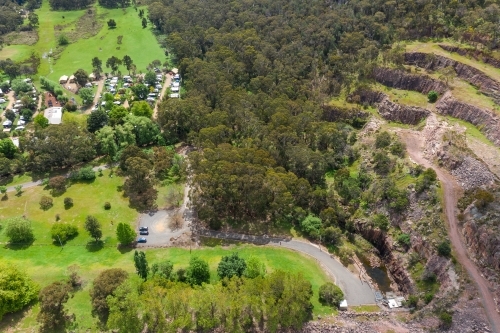 Aerial view of a green valley with a caravan park, forest and rocky terraces