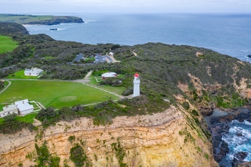Aerial view of a lighthouse perched on a clifftop above a rugged coastline
