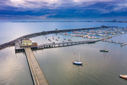 Aerial view of a long narrow jetty over a calm bay under a dark twilight sky - Australian Stock Image