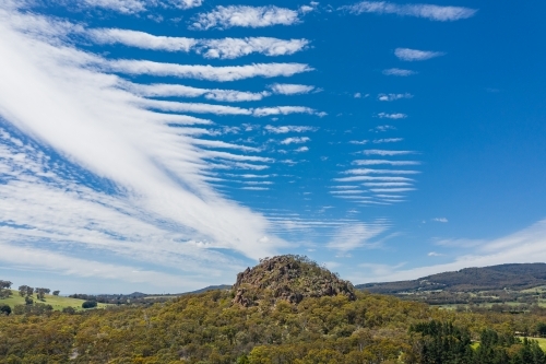 Aerial view of a mountainous rock formation with an unusual cloud formation above - Australian Stock Image