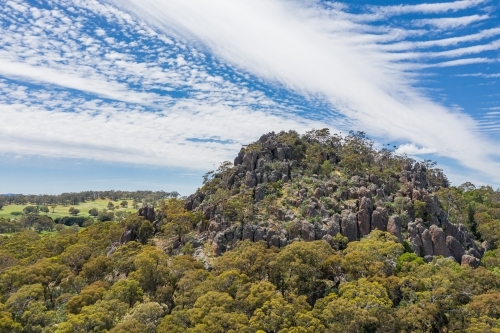 Aerial view of a mountainous rock formation with an unusual cloud formation above - Australian Stock Image