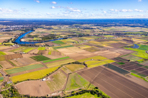 Aerial view of a patchwork farmland beside the meandering river - Australian Stock Image