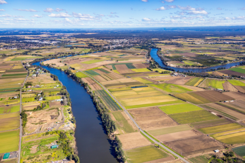 Aerial view of a patchwork farmland beside the meandering river - Australian Stock Image
