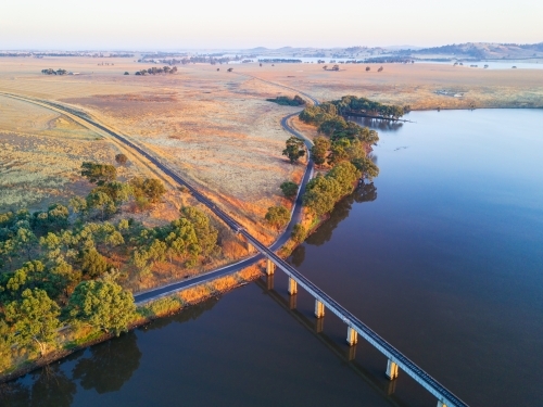 Aerial view of a railway bridge crossing a lake in early morning sunshine
