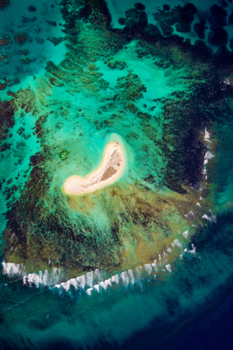 Aerial view of a remote sandy cay surrounded by coral reef and turquoise sea - Australian Stock Image