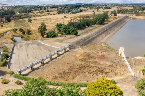 Aerial view of a reservoir and dam wall with a dry spillway. - Australian Stock Image