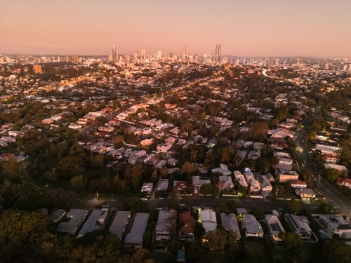 Aerial view of a residential area under the sunset sky with city skyline at the edge - Australian Stock Image
