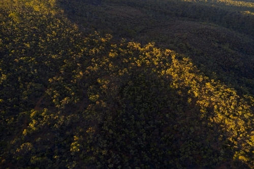 Aerial view of a ridge covered in bush in Western Australia, with contrasting light and shadow - Australian Stock Image