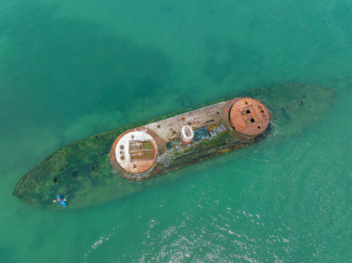 Aerial view of a rusty shipwreck in a shallow coastal bay - Australian Stock Image
