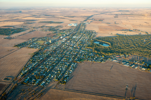 Aerial view of a small rural town showing grid streets surrounded by open agricultural farmland - Australian Stock Image