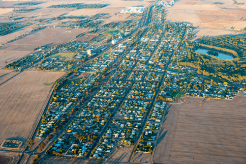 Aerial view of a small rural town showing grid streets surrounded by open agricultural farmland - Australian Stock Image