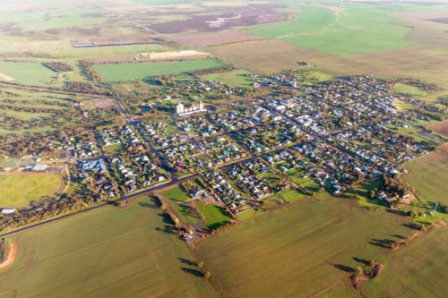 Aerial view of a small rural town surrounded by green farmland and open plains - Australian Stock Image