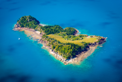 Aerial view of a small tropical island surrounded by turquoise water - Australian Stock Image