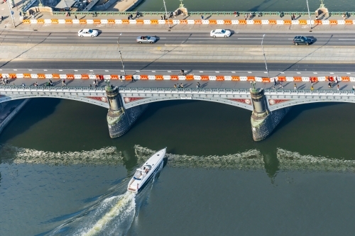Aerial view of a speedboat about to go under a bridge over a river - Australian Stock Image