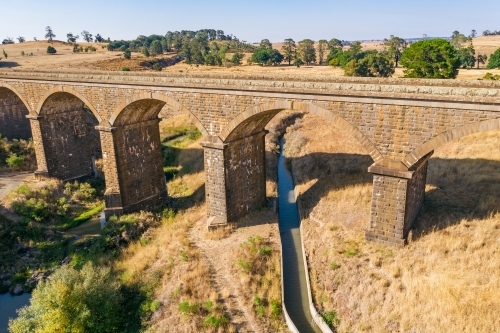 Aerial view of a stone viaduct over a river and water channel - Australian Stock Image