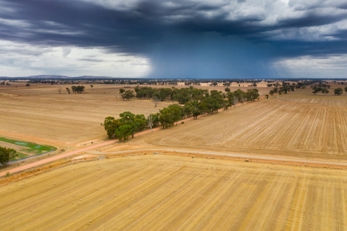 Aerial view of a storm cloud dropping rain on dry farmland - Australian Stock Image