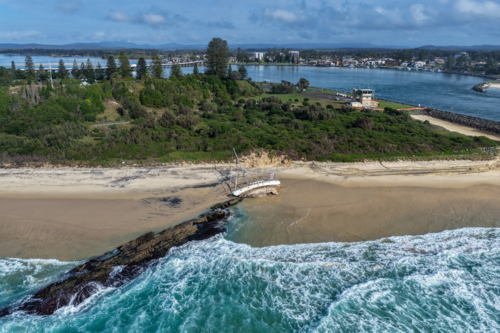 Aerial view of a stranded sailboat resting on the sand at Forster Main Beach. - Australian Stock Image
