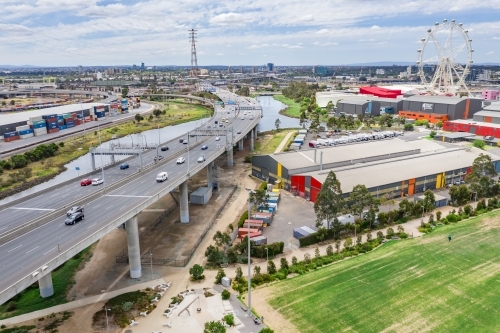 Aerial view of a wide freeway overpass with a sporting field below and ferris wheel in the distance