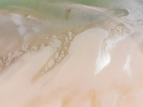 Aerial view of abstract patterns of tidal sand flats along a wide sandy beach - Australian Stock Image