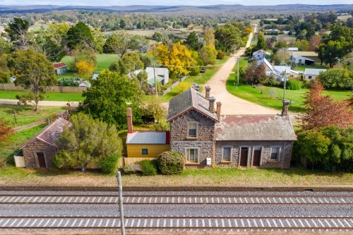 Aerial view of an deserted blue stone railway station with grass growing on the platform - Australian Stock Image