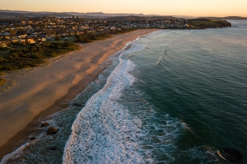 Aerial view of beach and coastal town at sunrise
