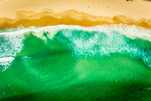 Aerial view of beach with turquoise waves, golden sand, and surfers in Bondi Beach. - Australian Stock Image