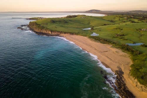 Aerial view of beached rolling green hills at sunrise - Australian Stock Image