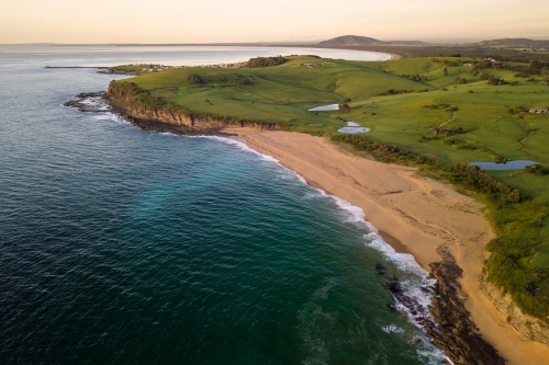 Aerial view of beached rolling green hills at sunrise