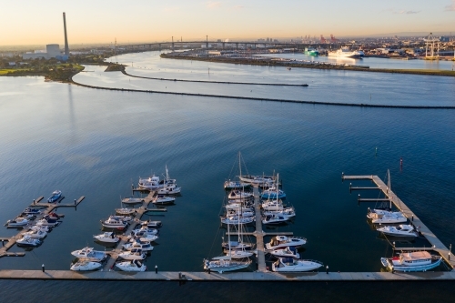 Aerial view of boats and yachts moored along jetties on a calm bay - Australian Stock Image